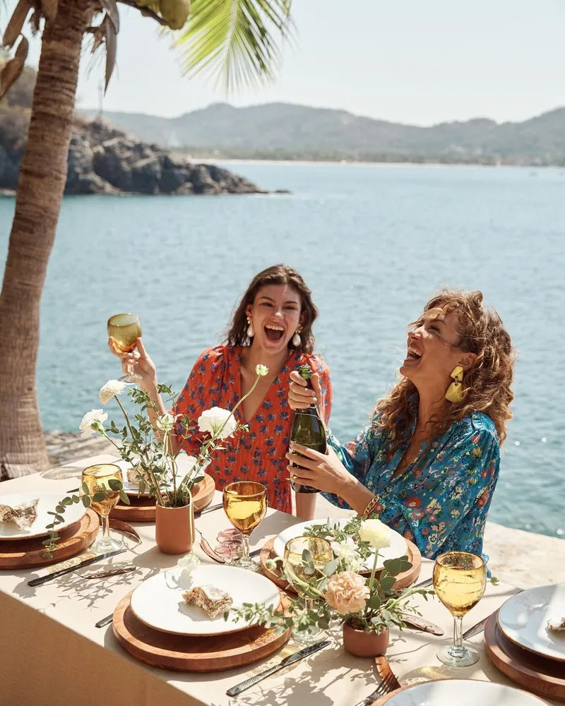 Friends laughing over lunch by the sea
